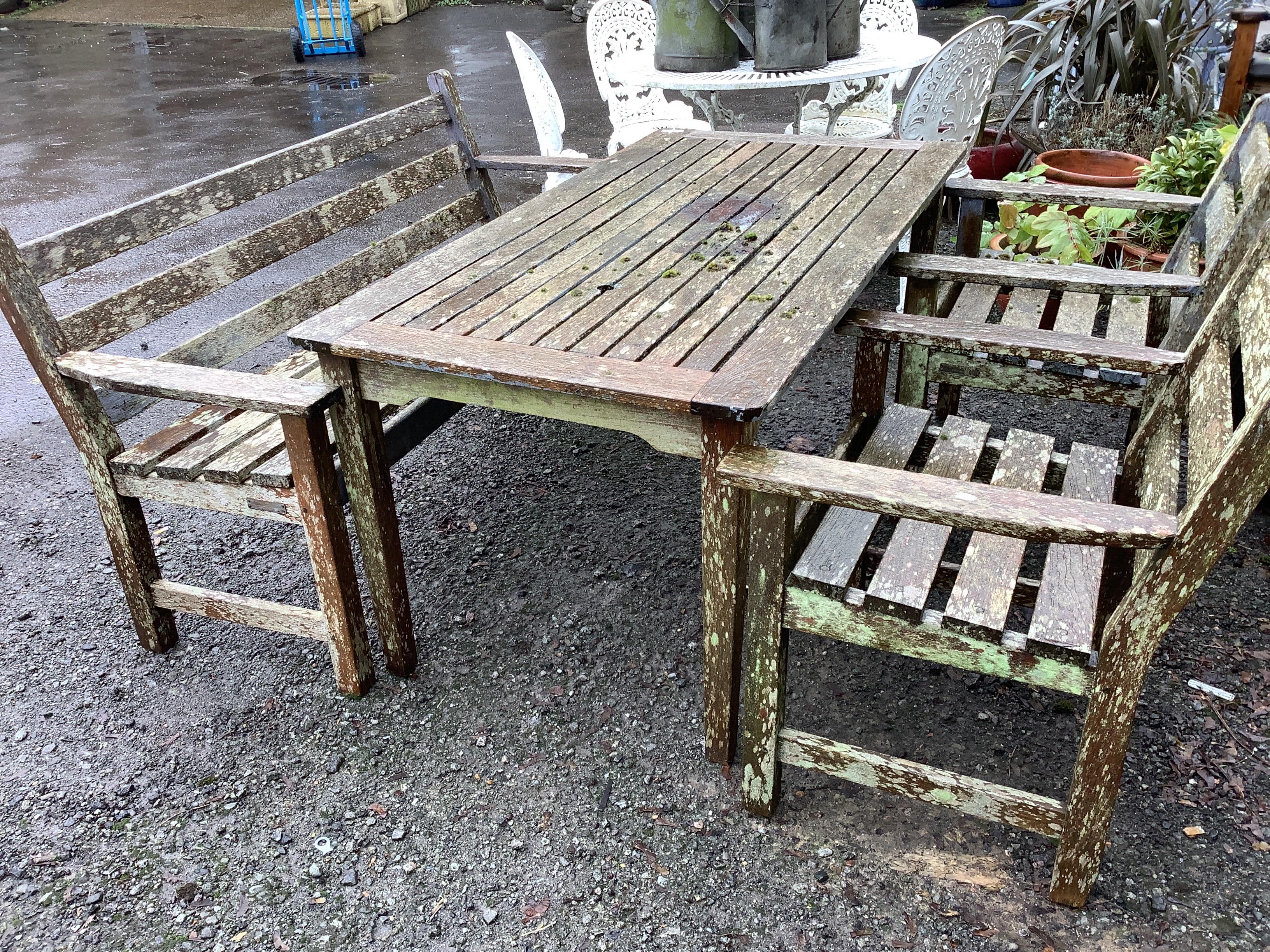 A rectangular teak garden table, width 152cm, depth 77cm, height 68cm, together with a slatted teak garden bench and two armchairs